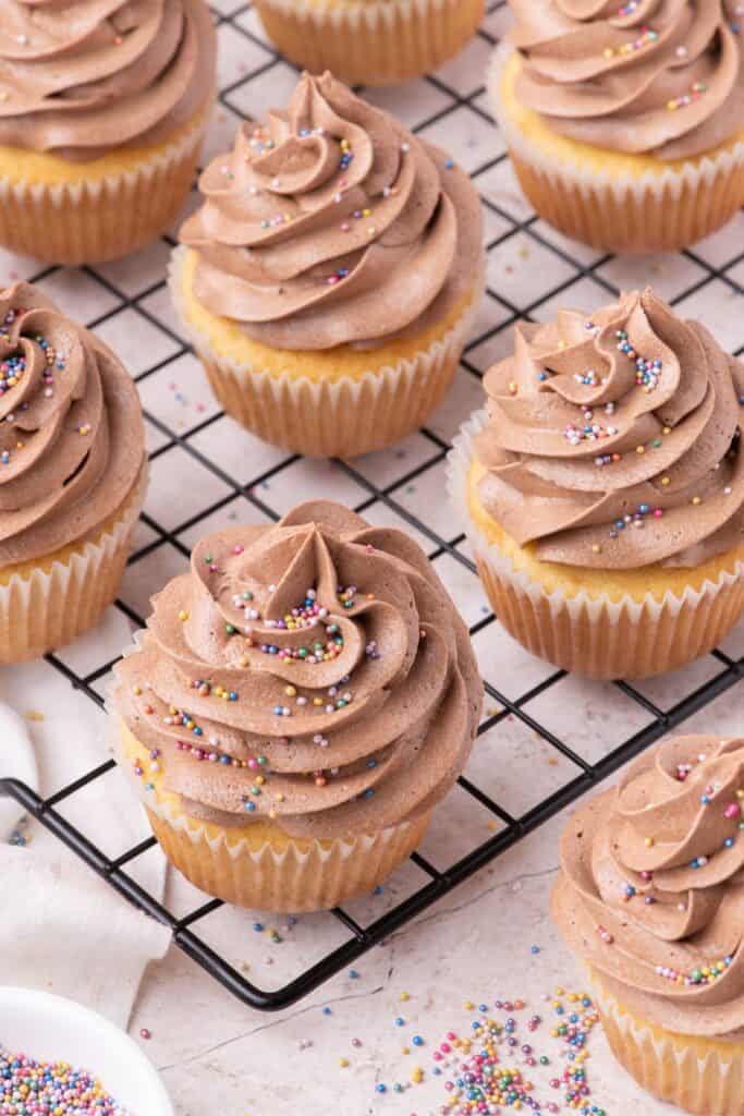 side view of frosted vanilla cupcakes with scattered sprinkles