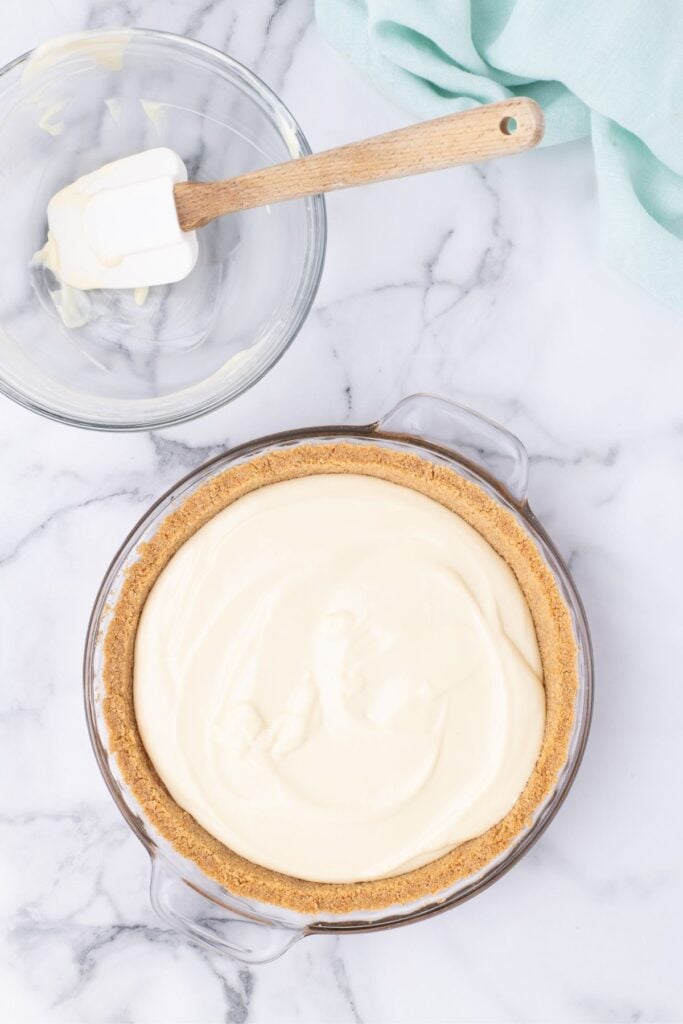 pouring key lime pie filling into cooked graham crust