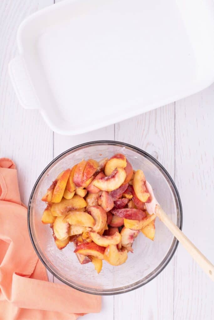 adding lemon juice and sugar to peaches in a bowl