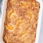 Top down view of the peach cobbler with cake mix in a baking dish out of the oven before being cut into.