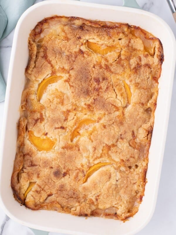 Top down view of the peach cobbler with cake mix in a baking dish out of the oven before being cut into.