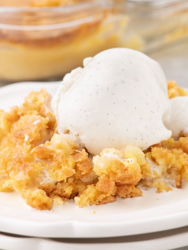 Pineapple Dump Cake on plate with scoop of vanilla ice cream.