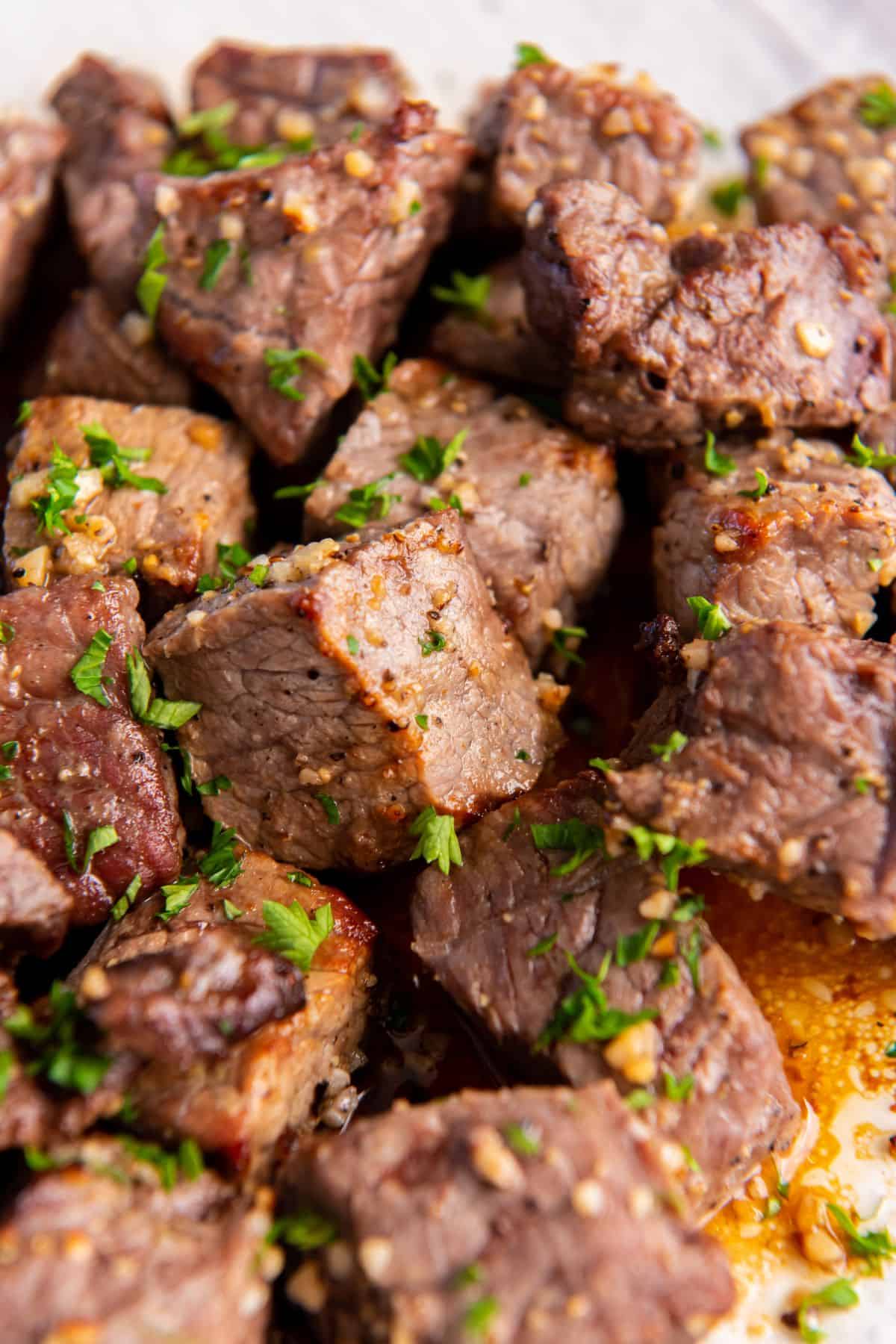 Close up of the cooked air fryer steak bites covered in garlic butter.
