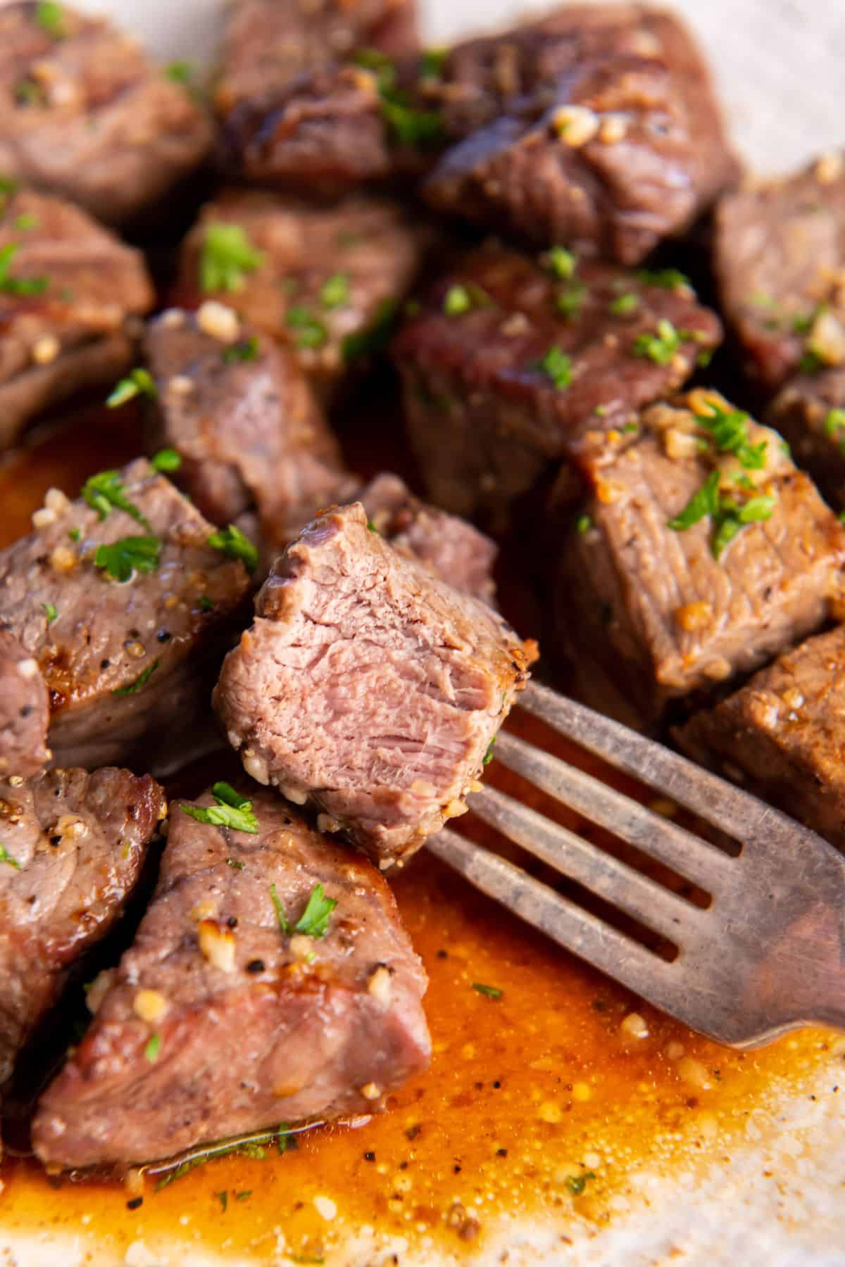 Close up of the steak bites with one with a bite taken out of it to see the inside.