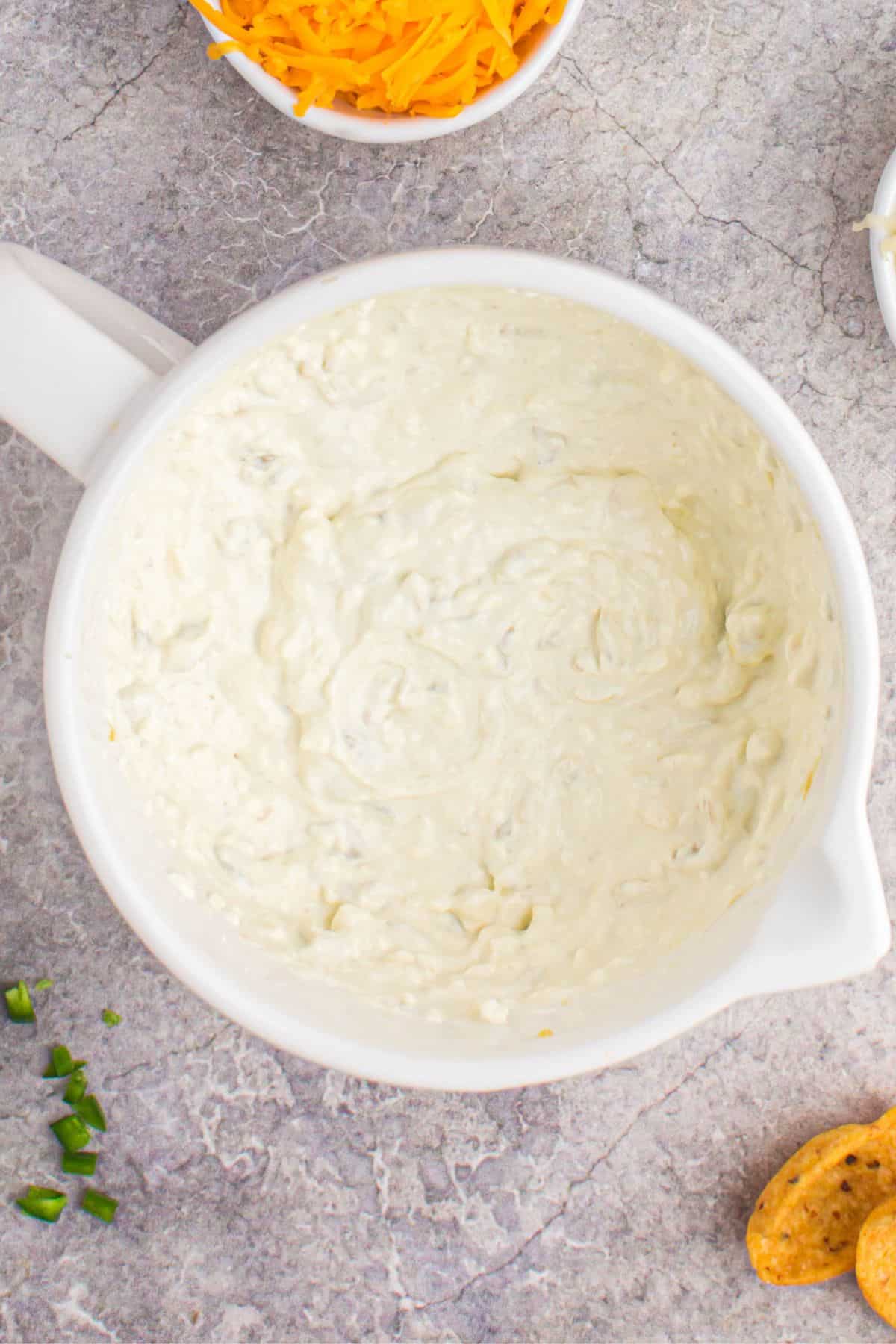 Green chilies, sour cream, and cream cheese all mixed in a mixing bowl to make the crack corn dip recipe.