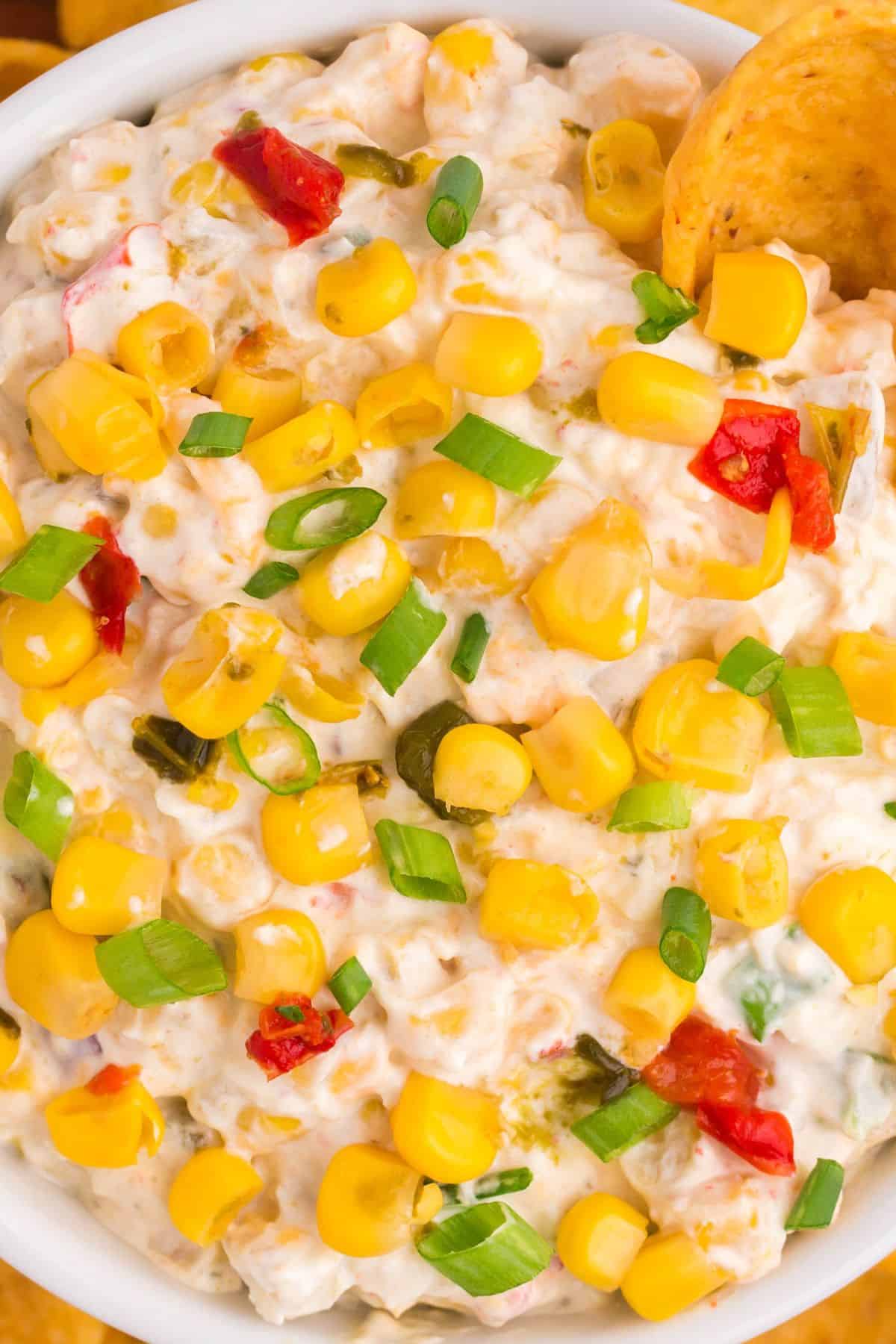 Close up view of the corn dip with fritos being dipped into it.
