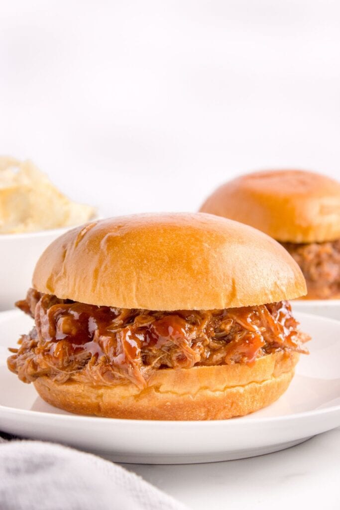 Pulled pork on a plate with BBQ sauce in a bun