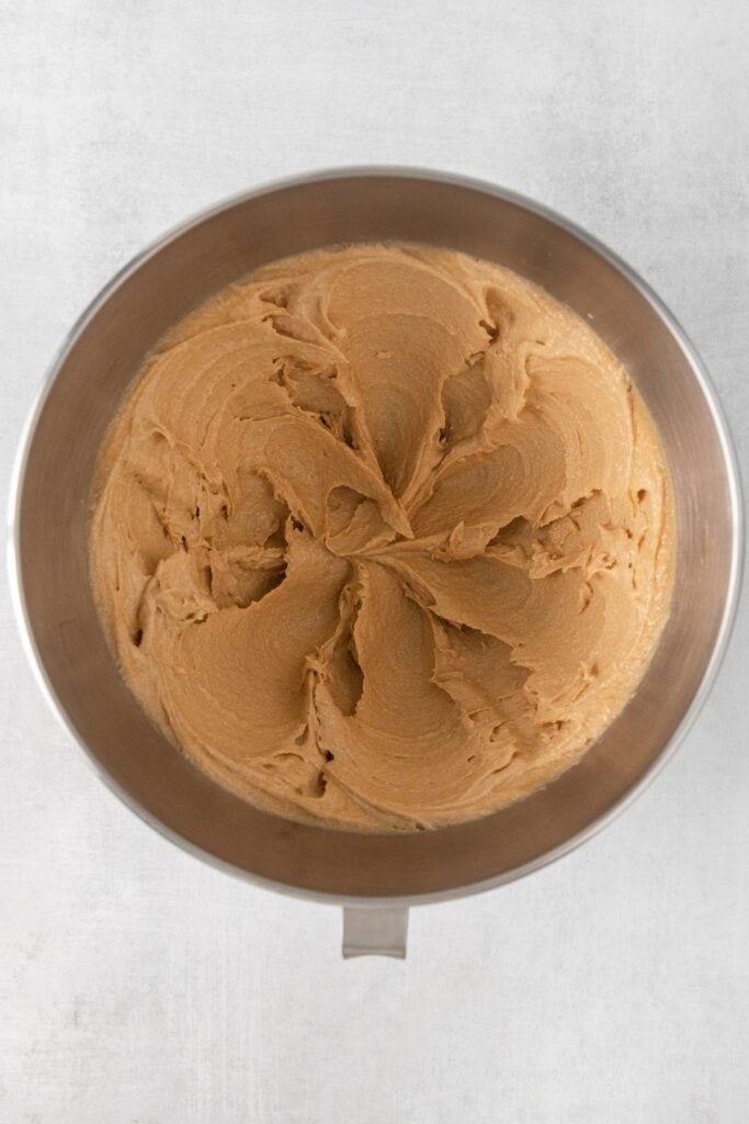 Butter, peanut butter, and brown sugar creamed in a mixing bowl to make peanut butter blossoms.