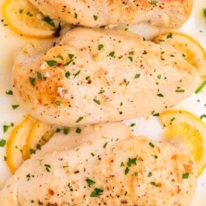 Lemon butter chicken with lemon slices on a white serving dish.