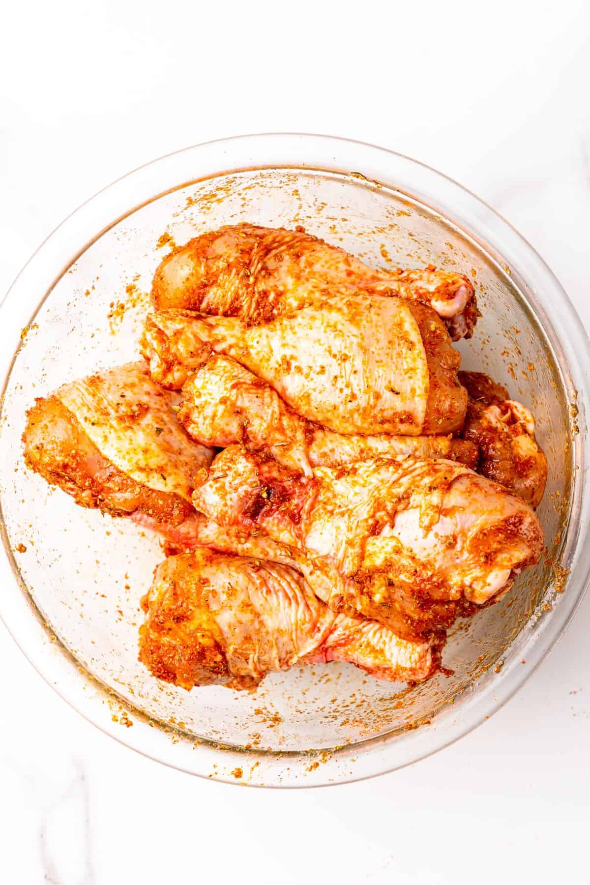 Seasonings mixed into the chicken legs in a bowl.