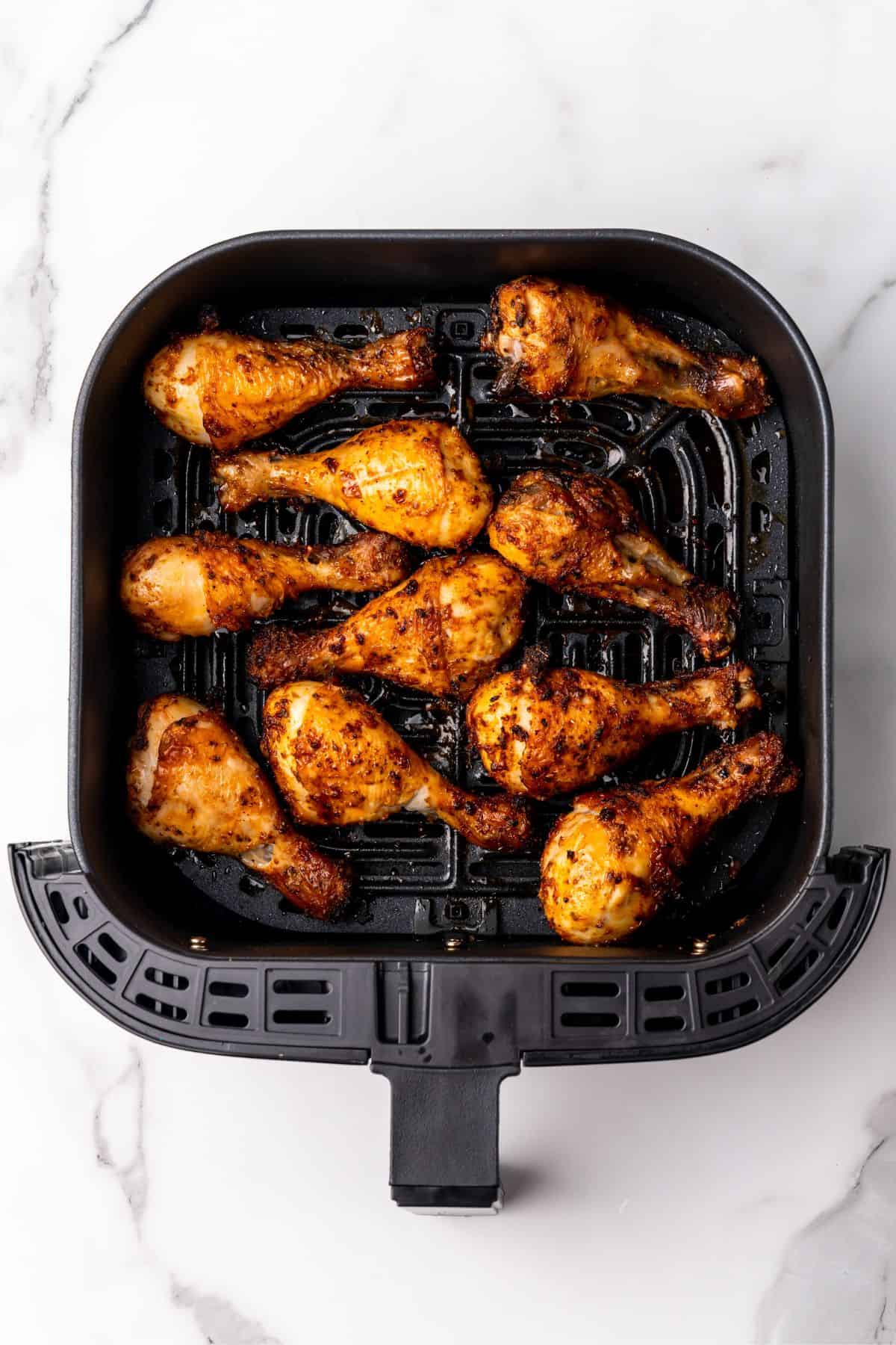 Cooked chicken legs in a square air fryer basket.