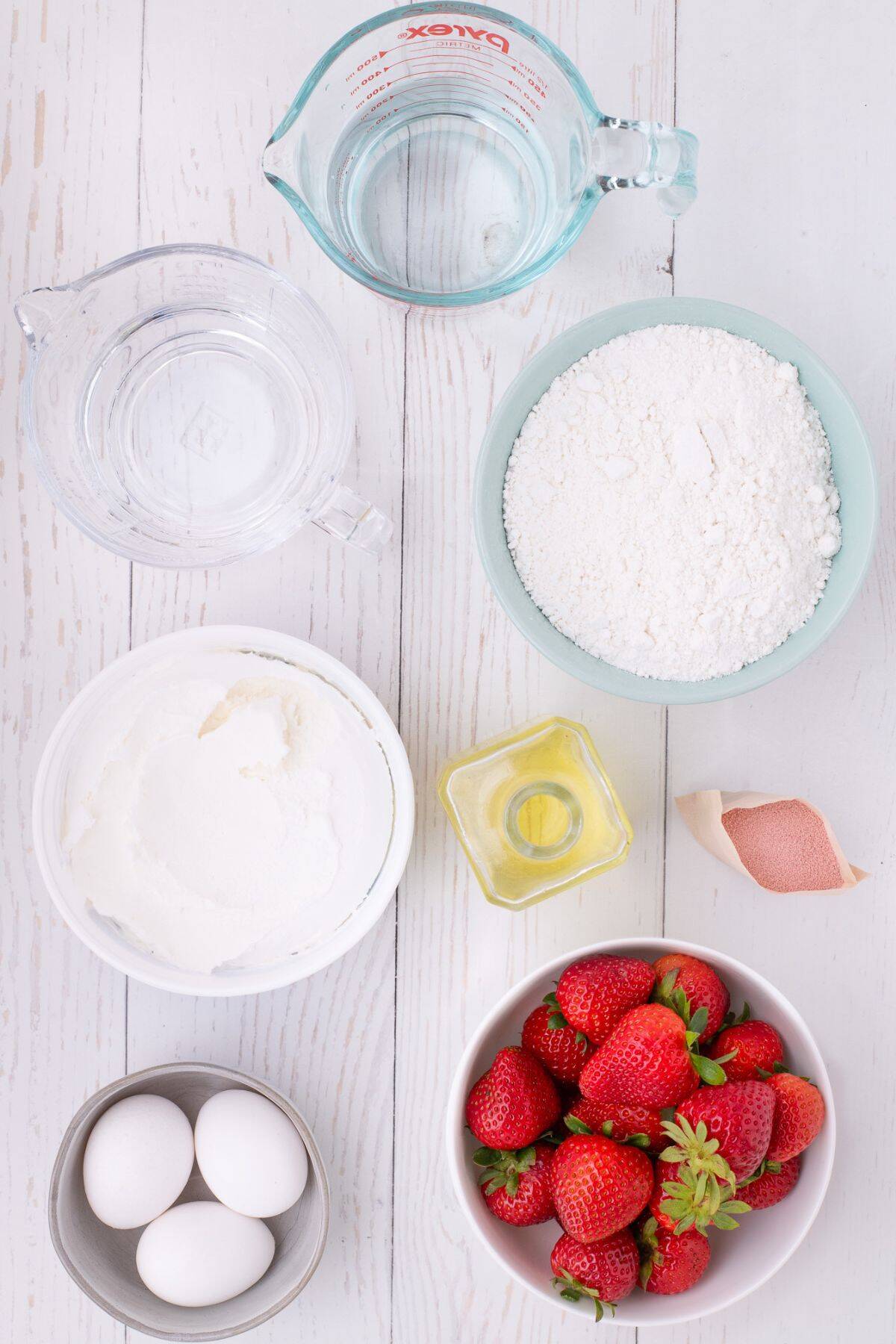Ingredients needed to make jello poke cake: cake mix, eggs, water, vegetable oil, strawberry jello, cool whip, and strawberries.