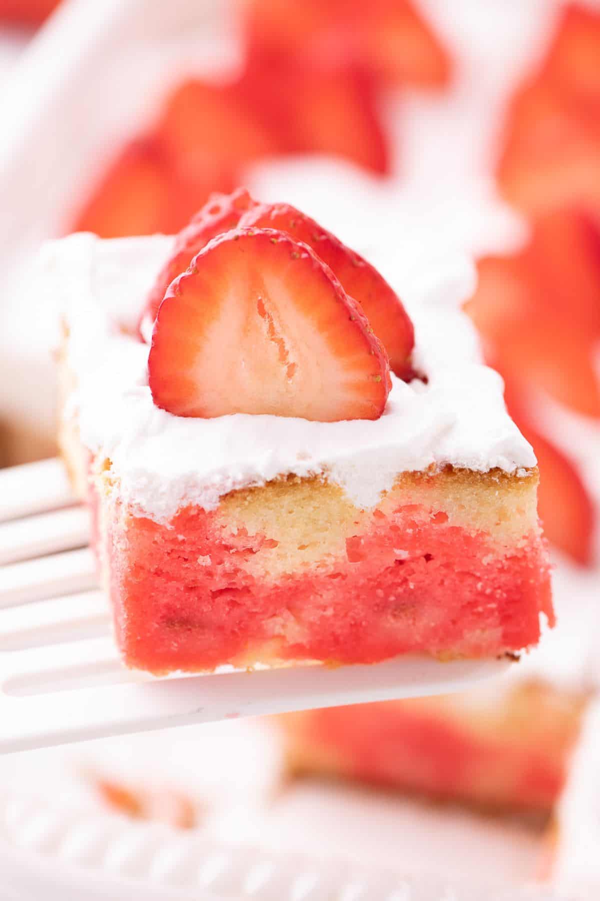 Close up view of a slice of jello poke cake to see the jello inside the cake.