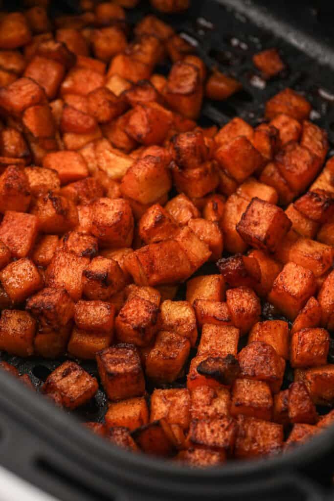 Close up of cooked butternut squash in an air fryer basket.