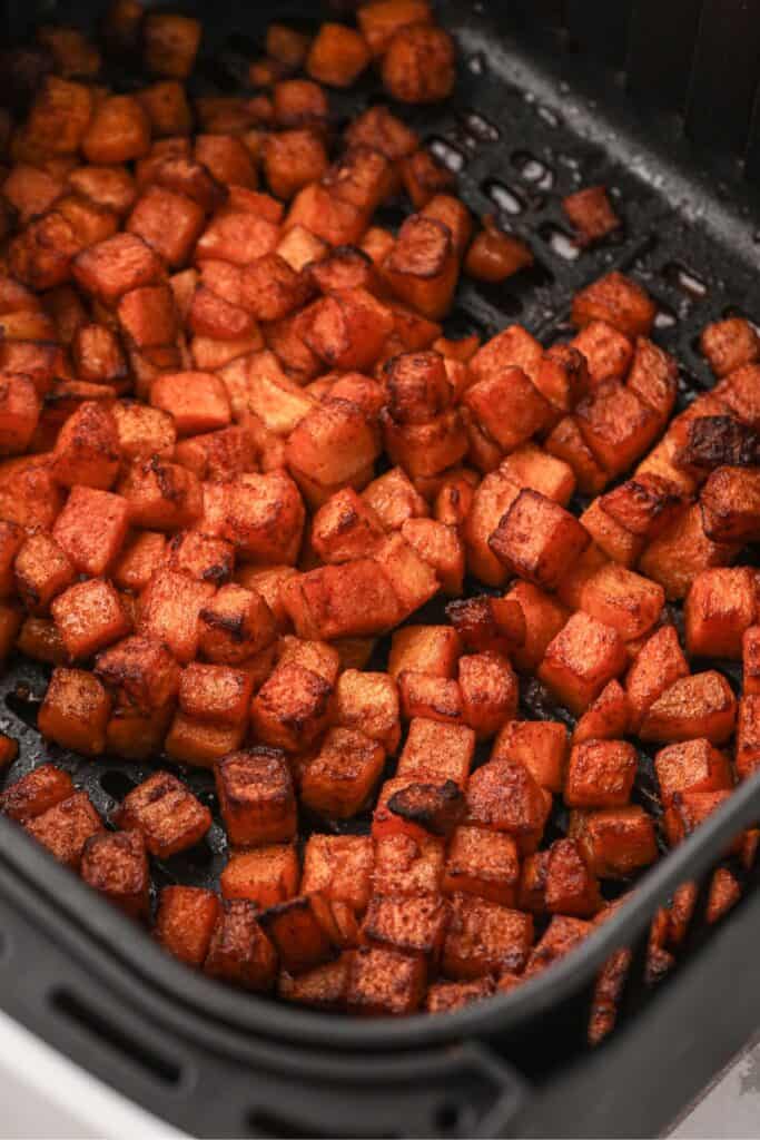 Air fryer butternut squash cooked and in an air fryer basket.