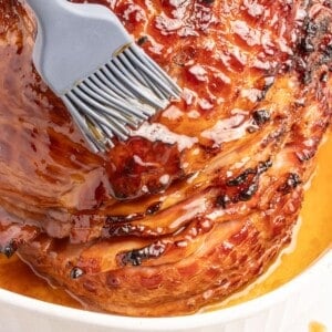 Close up of caramelized 3-ingredient ham glaze being brushed on a full ham.