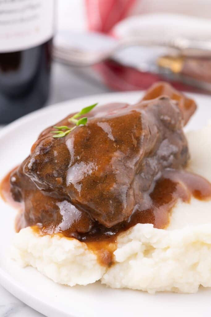 White dinner plate with mashed potatoes and short ribs.