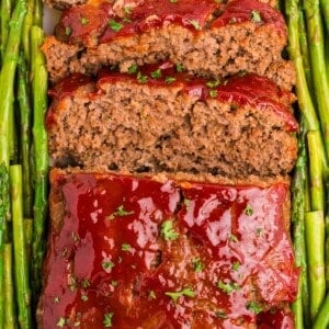 Completed and sliced meatloaf garnished with asparagus on both sides.
