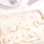Completed and iced cinnamon rolls in a baking pan.