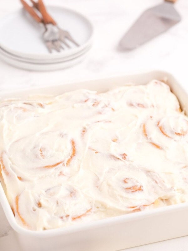 Completed and iced cinnamon rolls in a baking pan.