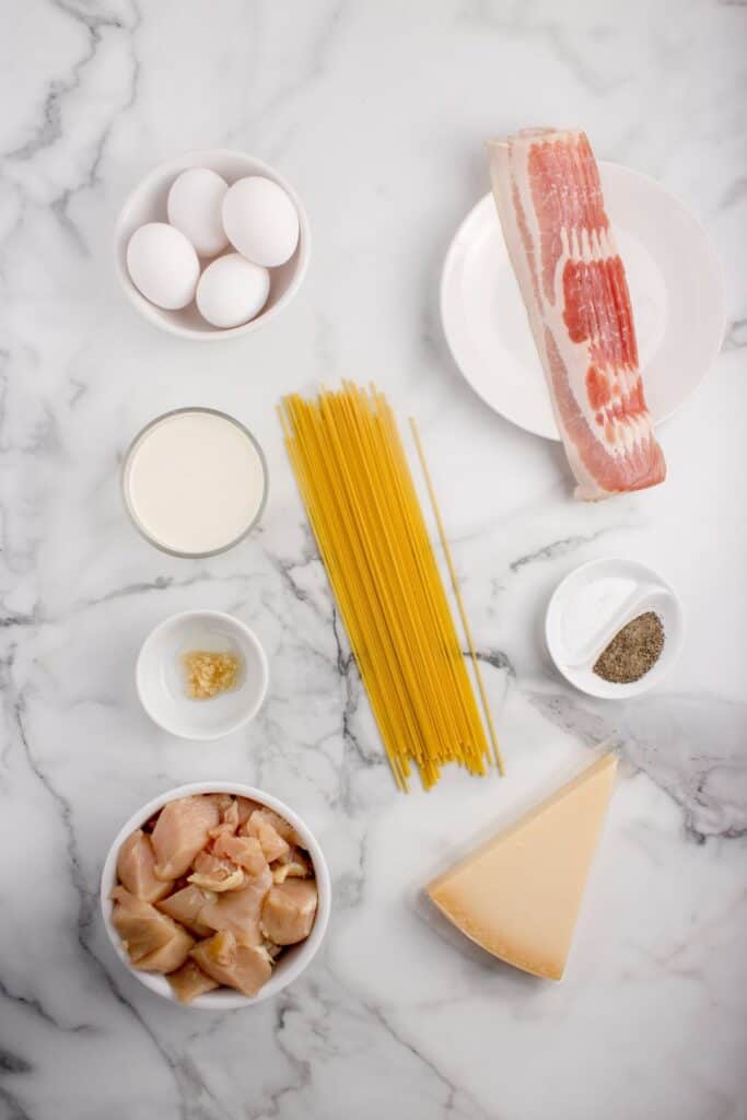 Ingredients for chicken carbonara: spaghetti noodles, bacon, chicken breasts, garlic, eggs, egg yolks, Parmesan cheese, heavy cream, salt, black pepper, and parsley.