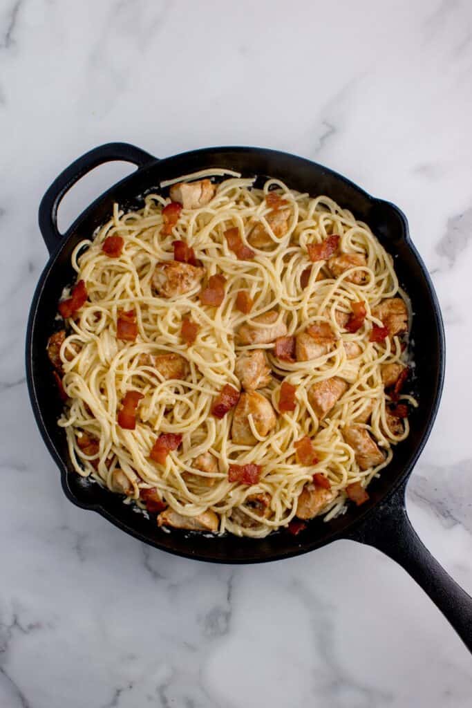 Cast iron pan with carbonara, spaghetti, chicken, and bacon.