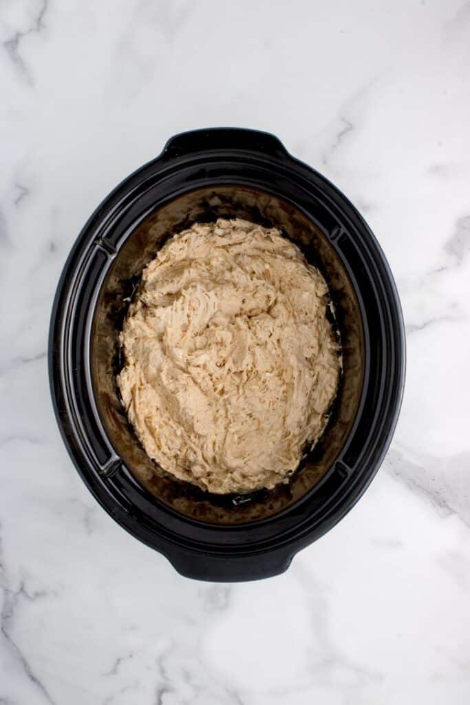 Slow cooker insert with shredded chicken.