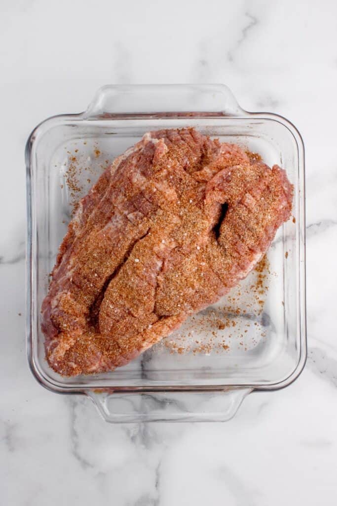 Seasoned pork shoulder in a glass baking dish.