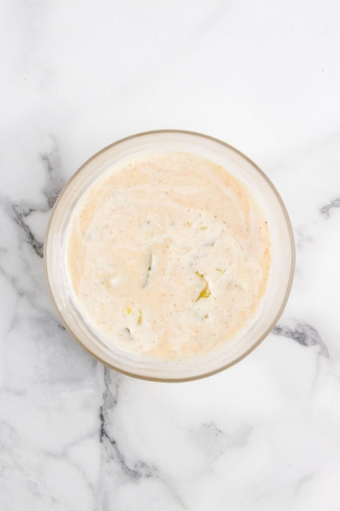 Dressing for coleslaw in a glass bowl.