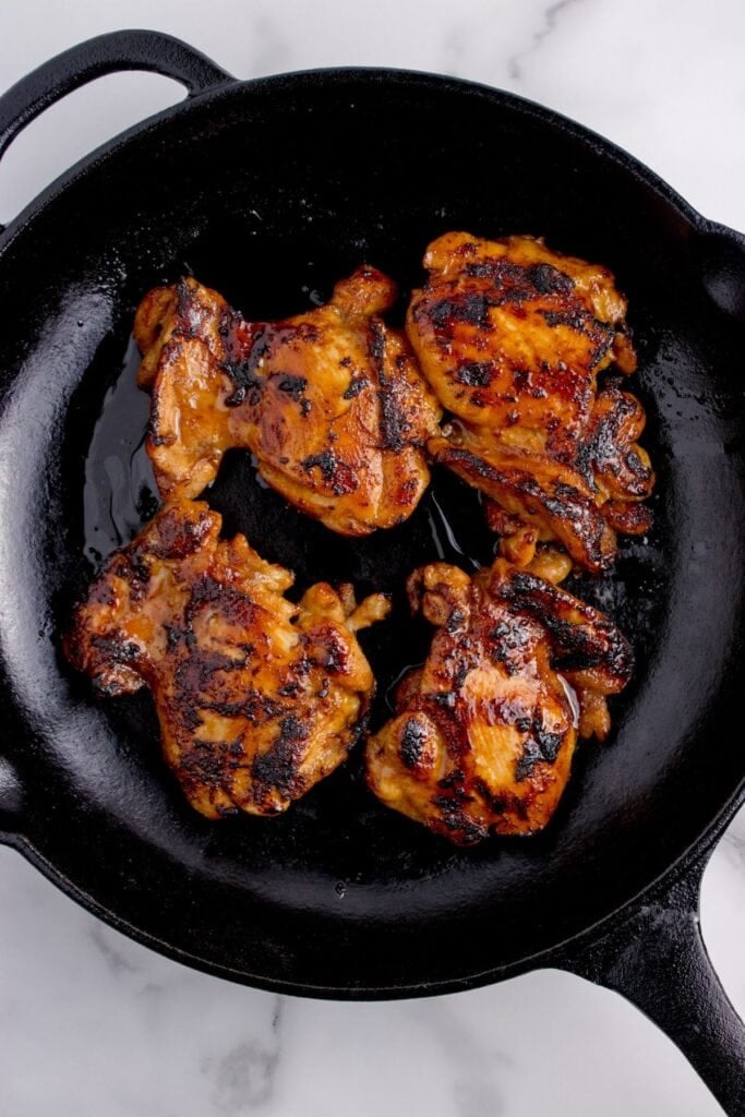 Cast iron pan with cooked chicken thighs.