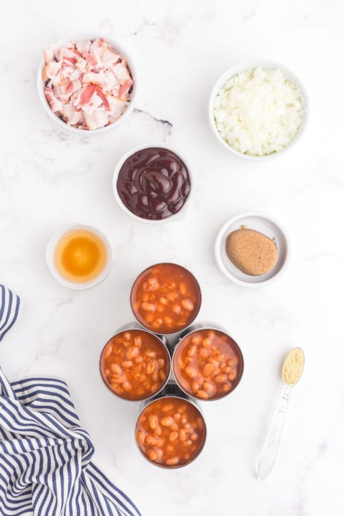 Ingredients for Baked Beans: canned pork and beans, bacon, onion, BBQ Sauce, dark brown sugar, Dijon mustard, and apple cider vinegar.