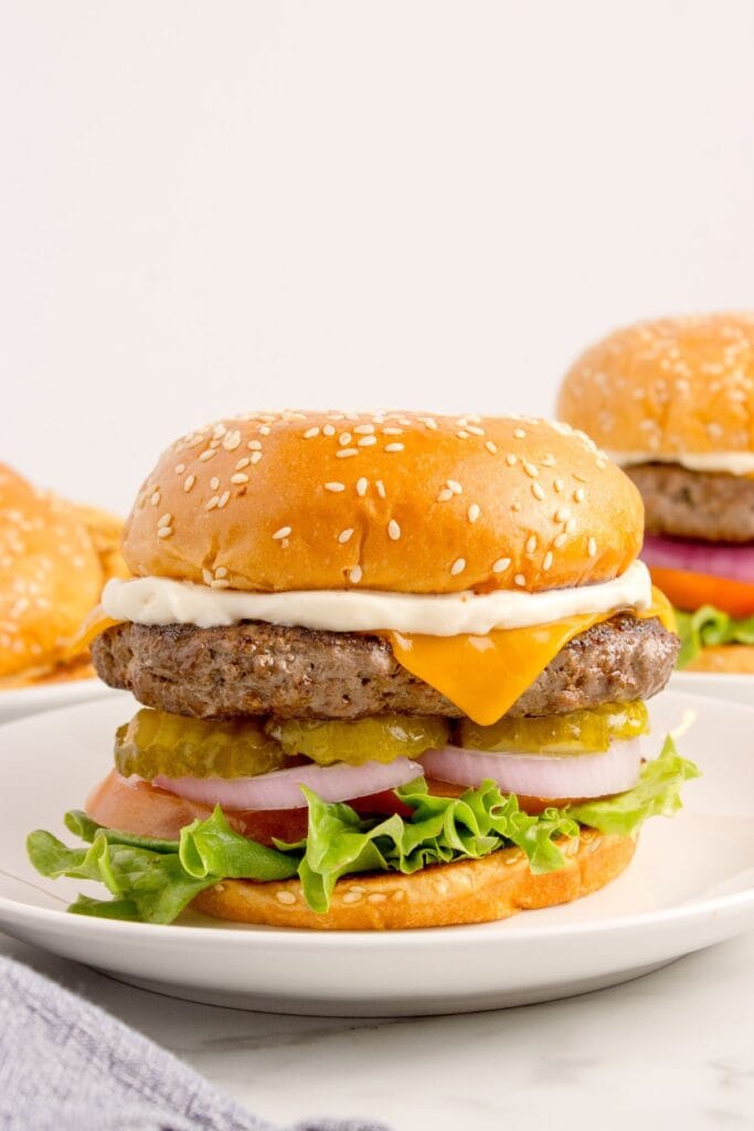 Bison burgers on white dinner plates.