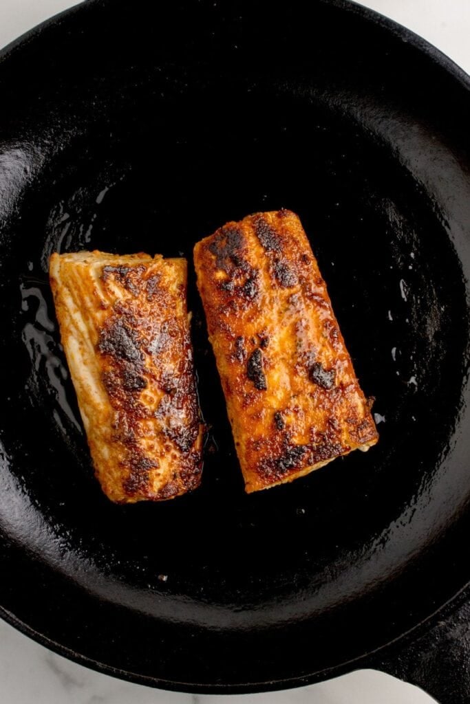 Two cooked mahi mahi fillets in a cast iron pan
