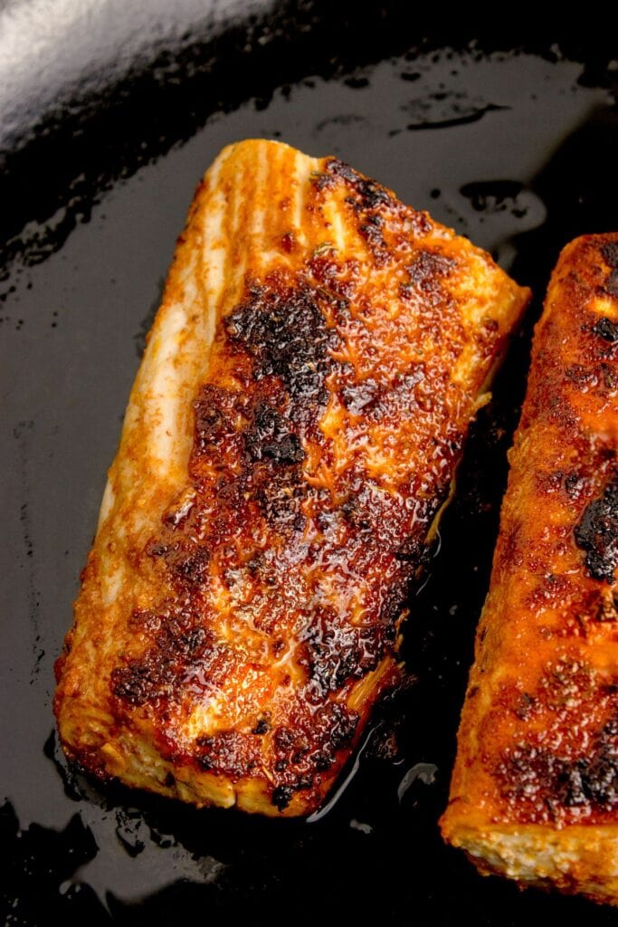Two cooked mahi mahi fillets in a cast iron pan