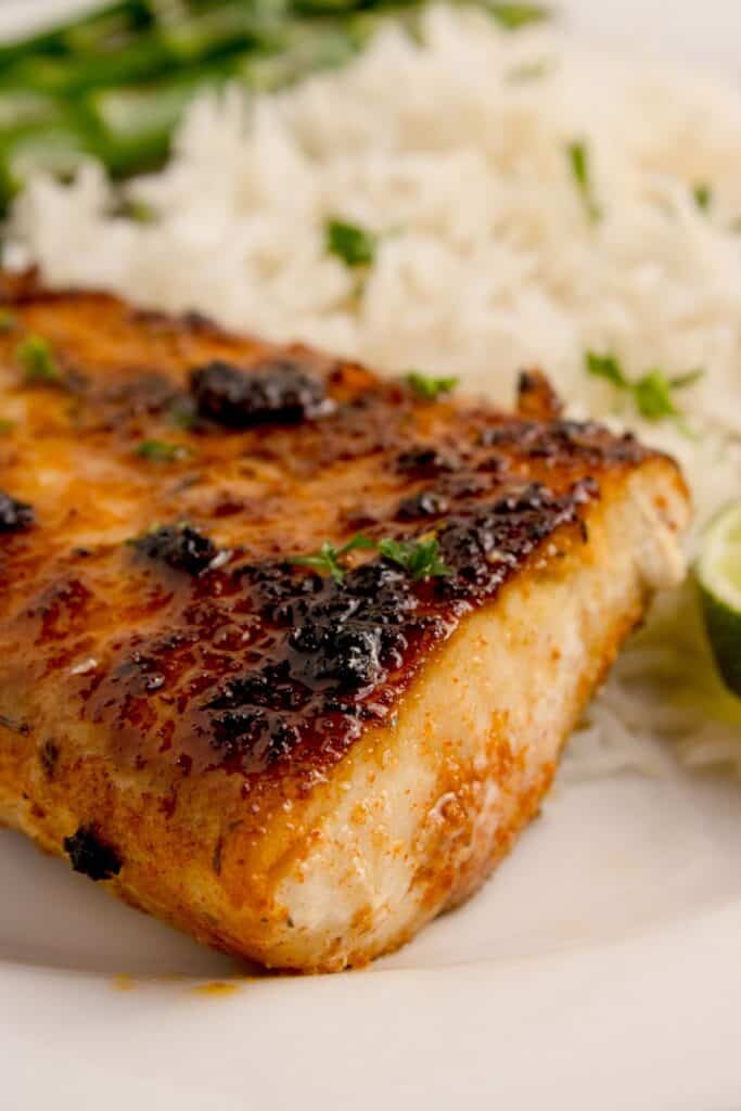 Blackened mahi mahi fillet on a white dinner plate.