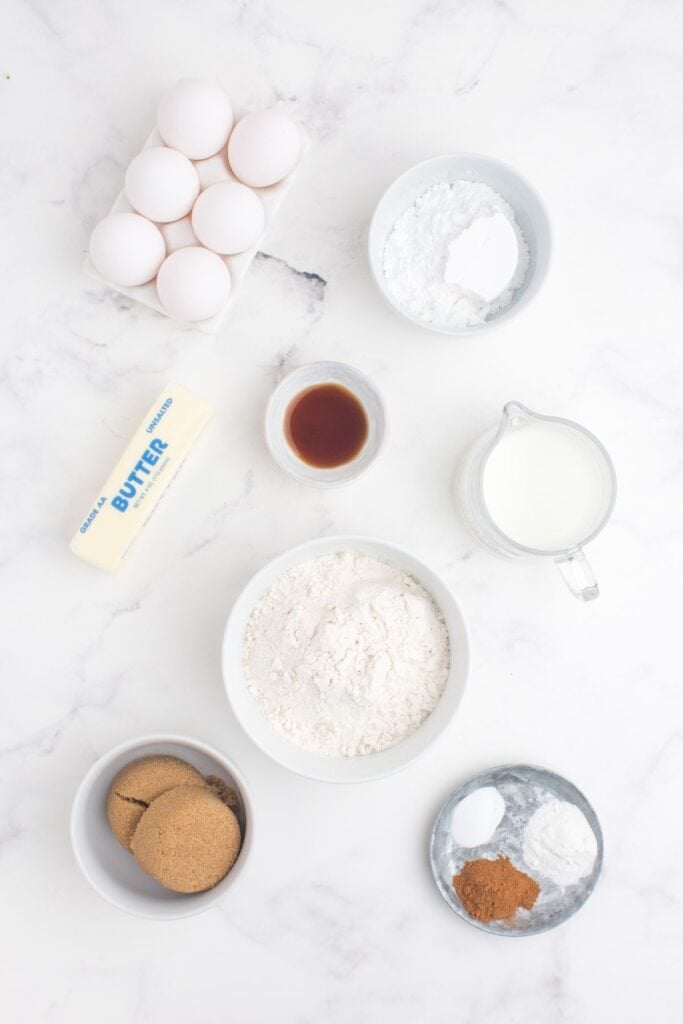 Ingredients for coffee cake muffins: all purpose flour, brown sugar, cinnamon, butter, baking powder, baking soda, ground cinnamon, milk, eggs, vanilla extract, and powdered sugar.