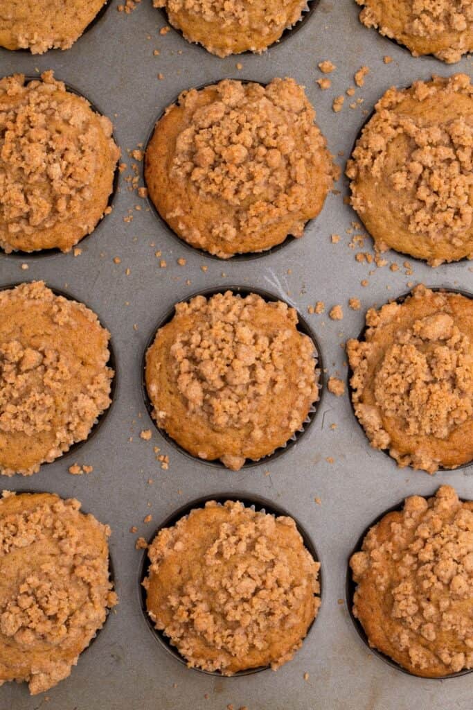 Muffin baking pan with baked coffee cake muffins in it.