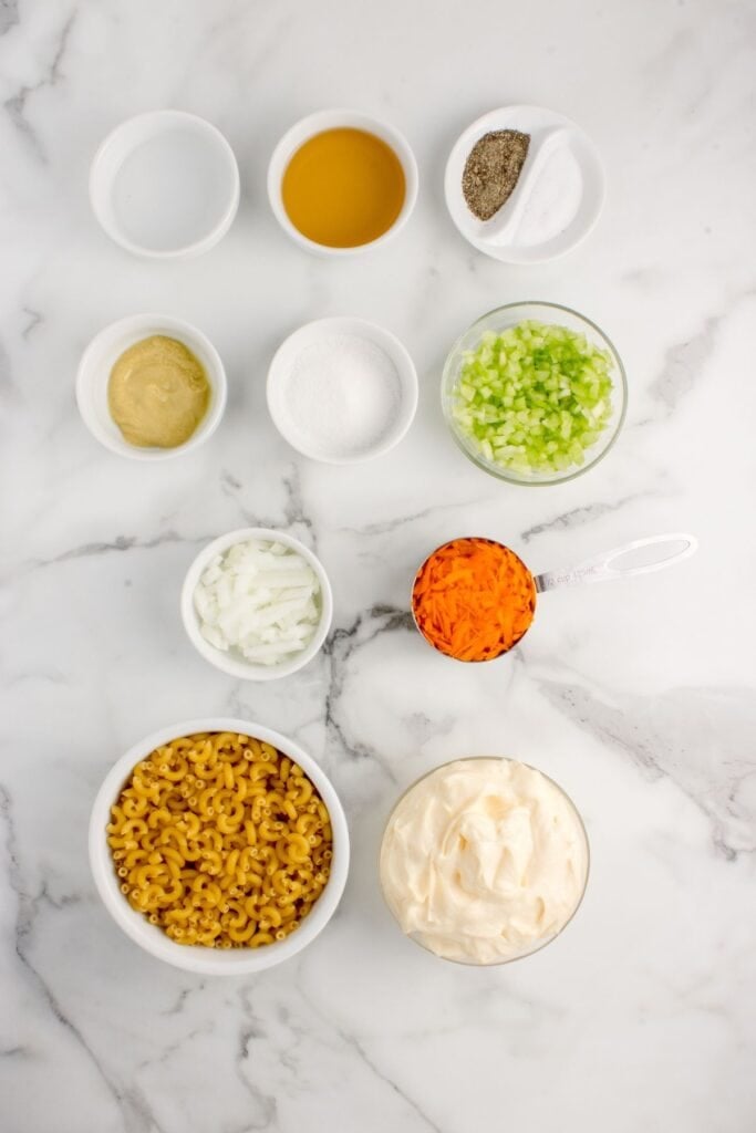 Ingredients for Easy Macaroni Salad: elbow noodles, mayo, celery, sweet onion, grated carrot, white vinegar, apple cider vinegar, dijon mustard, sugar, salt, and pepper.