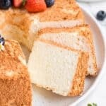 Angel food cake recipe without cake flour cut into slices with strawberries and blueberries on top.