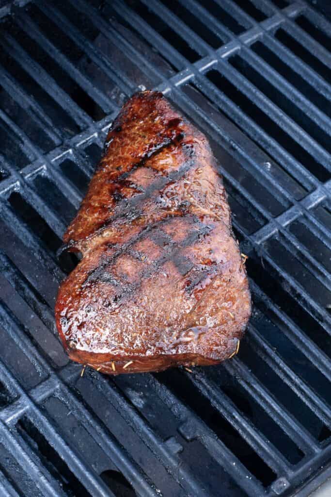 London broil cooking on a grill.