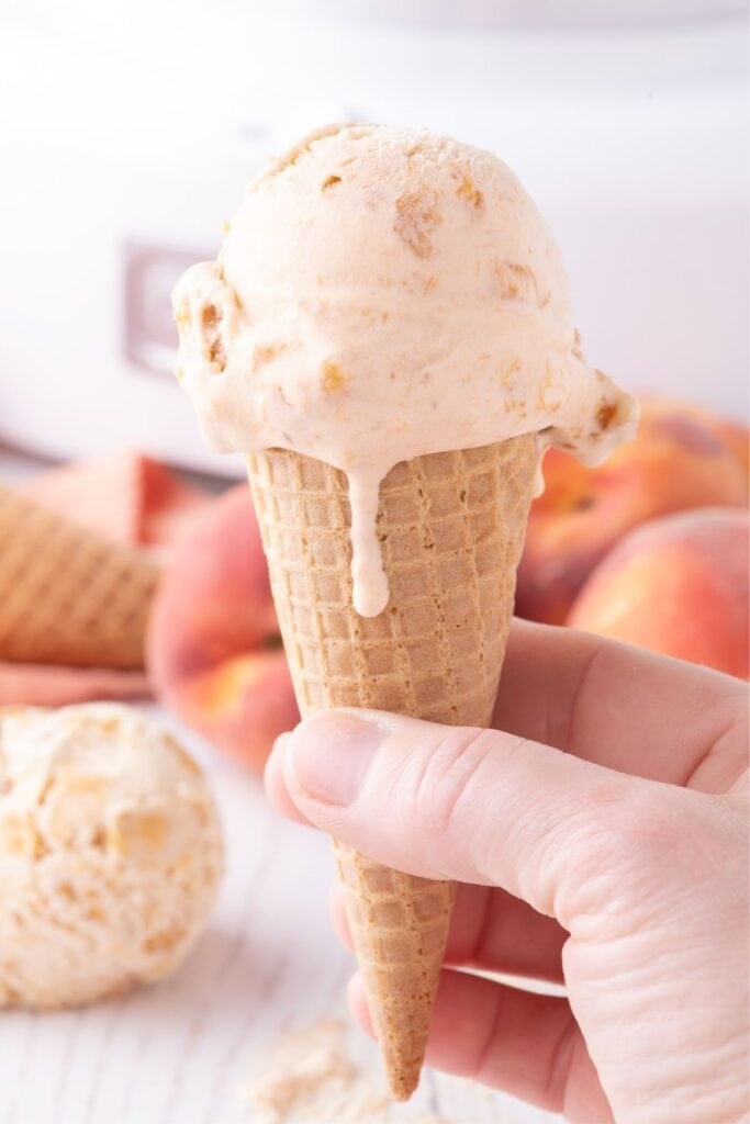 A scoop of peach ice cream on a sugar cone.