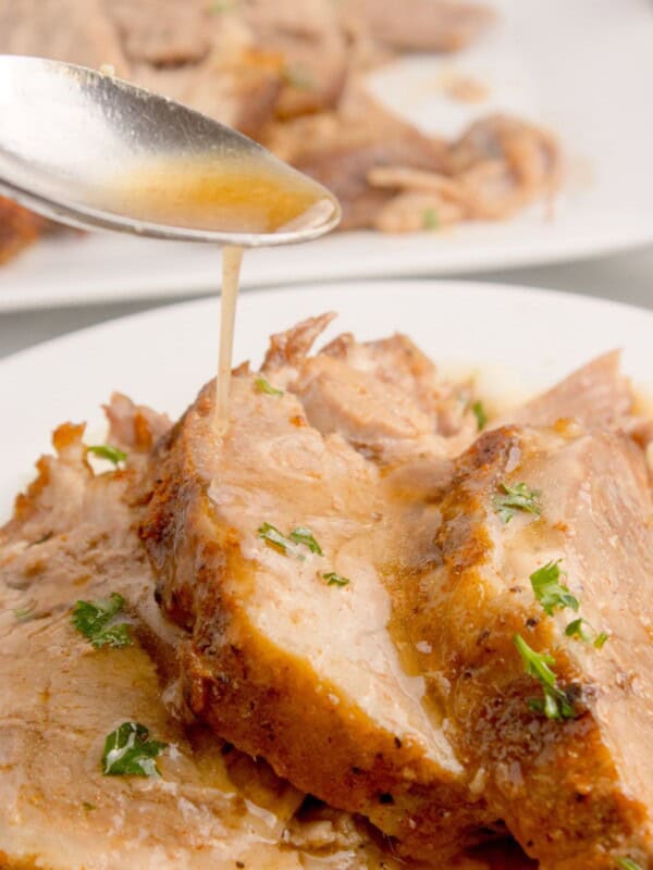 Au jus style juices being poured over the top of sliced pork roast.
