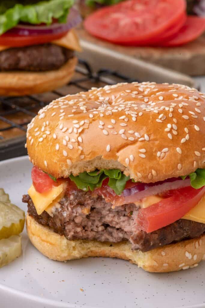 baked hamburger on a bun with a bite taken out of it.