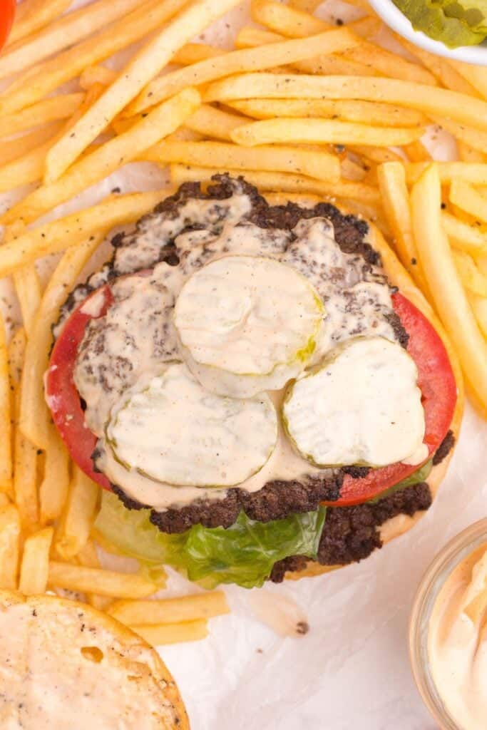 Classic smashburger with top bun off. Topped with 2 patties, lettuce, tomato, pickles and smash burger sauce. Surrounded by french fries.
