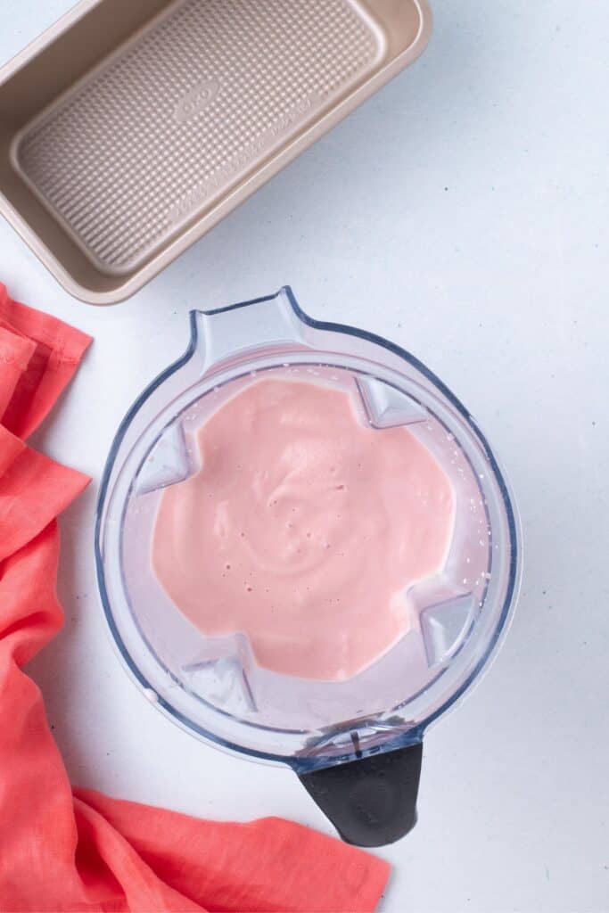 High powered blender with ice cream base in it. A pan is prepped next to the blender.