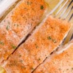 Four salmon filets in a white baking dish.