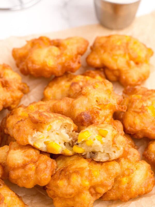 Corn Nuggets in a pile on parchment paper. The top nugget is broken in half to show interior.