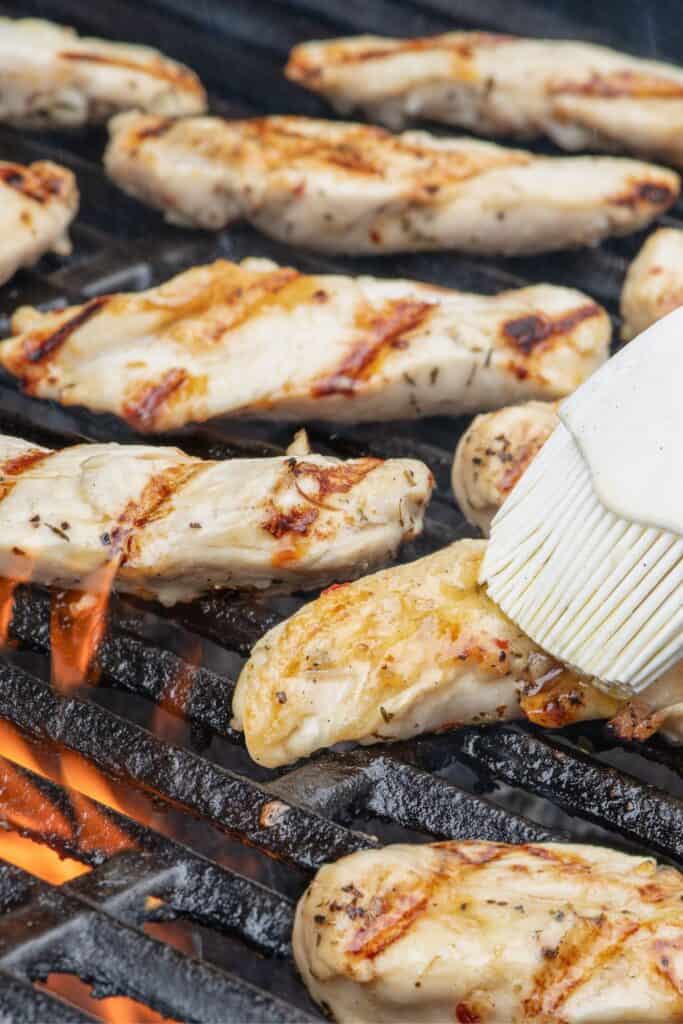 Chicken tenders cooking on grill grates.
