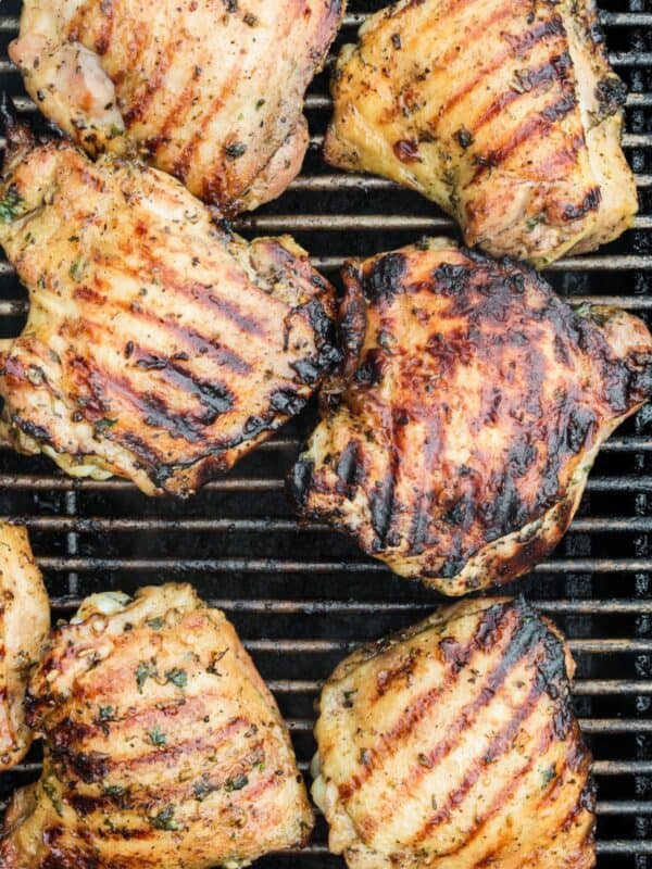 Grilling chicken thighs with the grill marks and slight char marks on them.