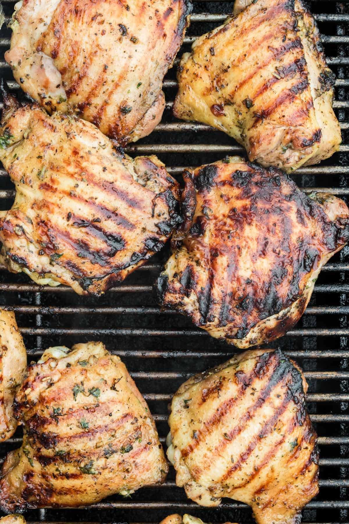 Grilling chicken thighs with the grill marks and slight char marks on them.